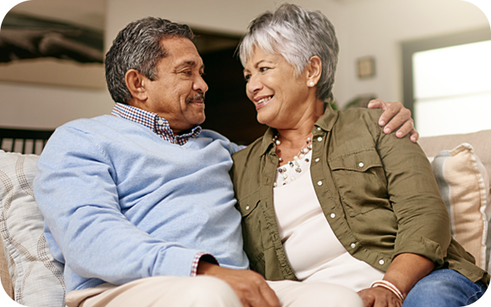 Elderly couple sitting closely together on a coach, smiling and looking at each other. Elderly couple sitting closely together on a coach, smiling and looking at each other.