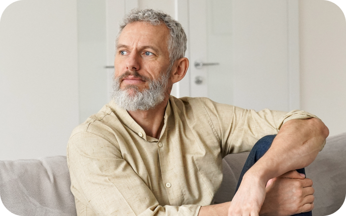 Older man looking out the window while sitting on his sofa.