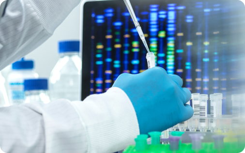 Gloved hand pipetting behind a of a colorful test tube rack.