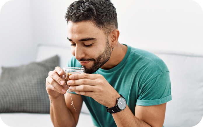 Young man sitting at home enjoying a glass of tea. Young man sitting at home enjoying a glass of tea.