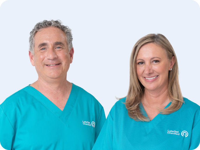 Two smiling clinicians wearing LetsGetChecked teal scrubs, standing side by side.