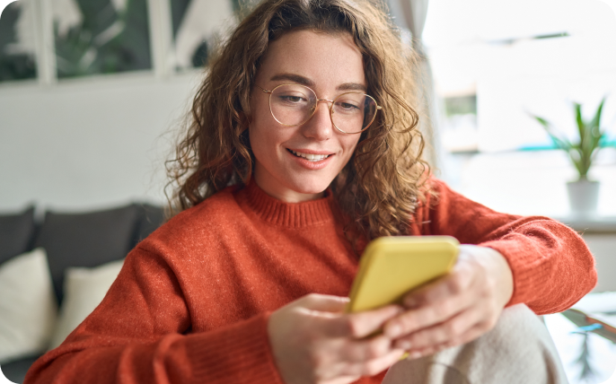 Woman smiling at her phone while sitting at home.