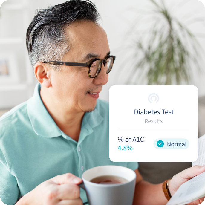Older man having a cup of tea, with a phone pop-up that reads "Diabetes, percentage of A1C, Normal".