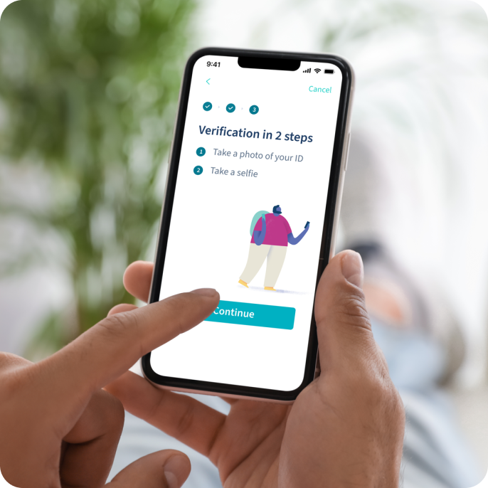 Close-up of a person's hands holding a smartphone showing the LetsGetChecked app screen with a two-step verification process, including photo ID and selfie instructions.