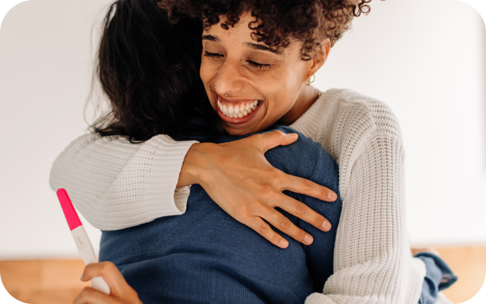 Two women embracing each other after receiving pregnancy test results.