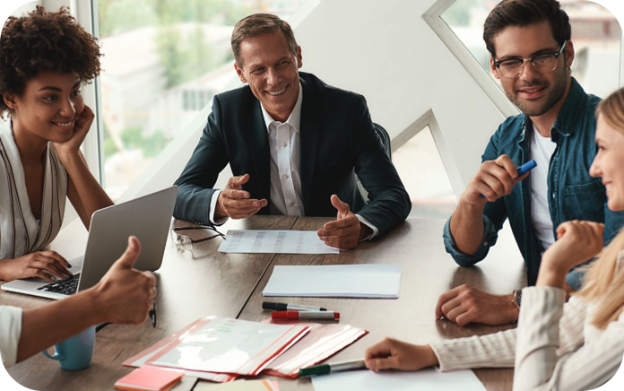 Group of colleagues in a meeting room having a discussion around a table.