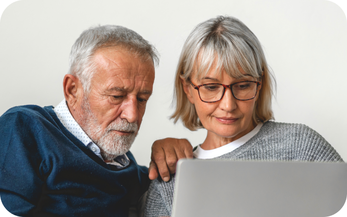 Elderly couple looking at a laptop screen together.