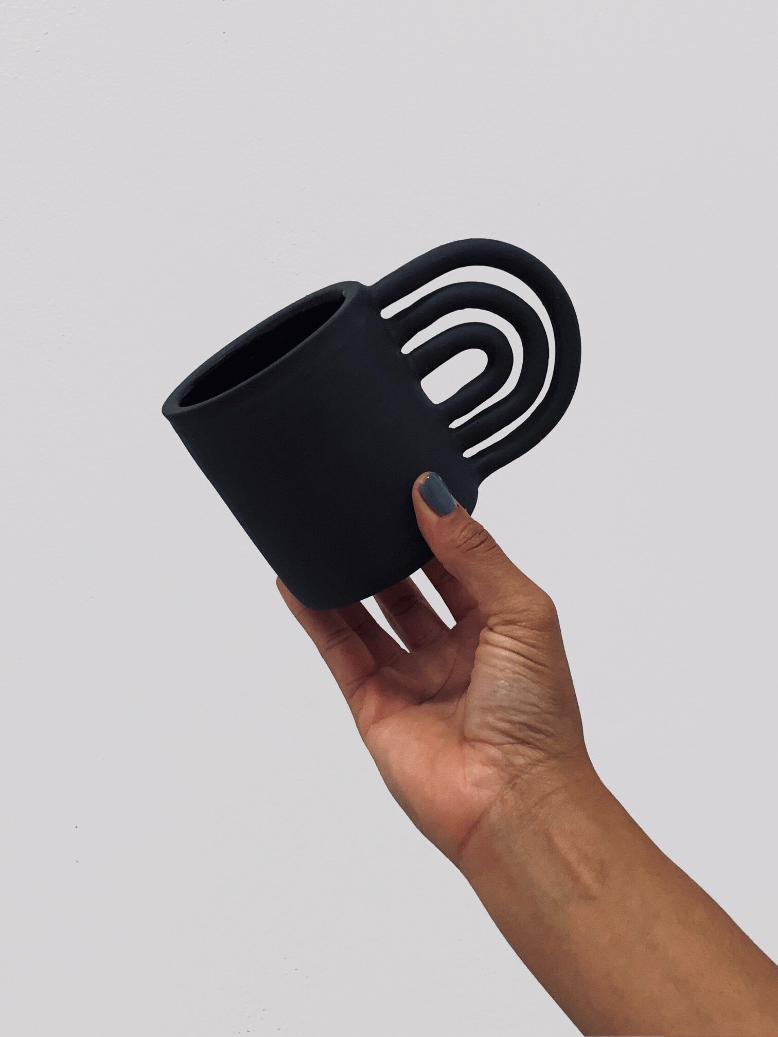 Black ceramic mug with rainbow shaped handle