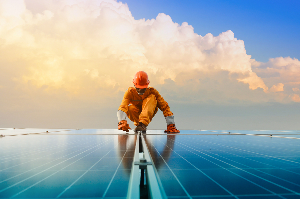 a man kneeling on a ladder on a solar panel