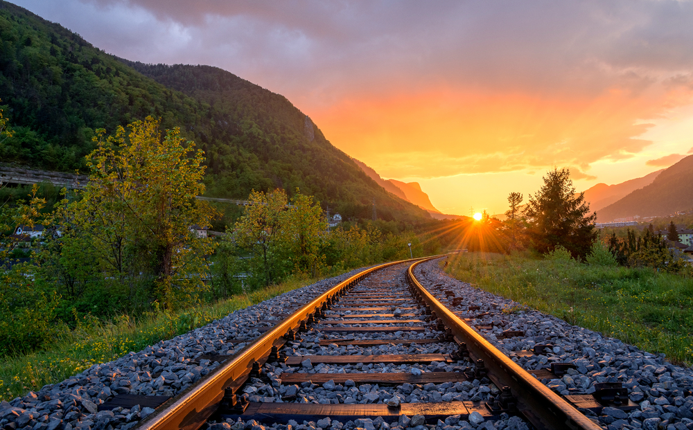 train tracks in a grassy area with a sunset in the background