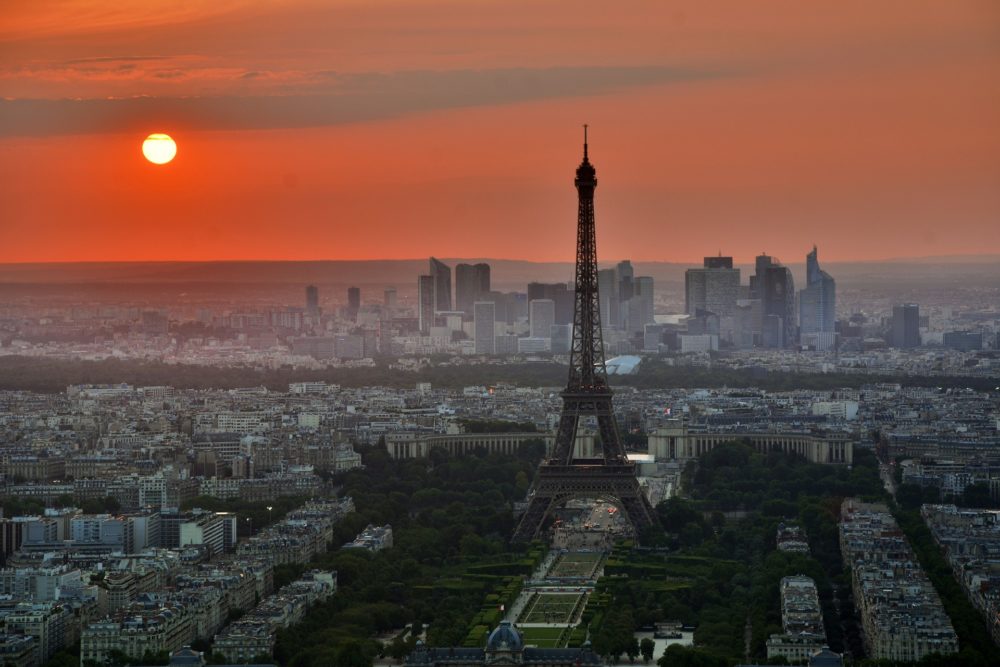 a large city with a tall pointy tower and a red sky