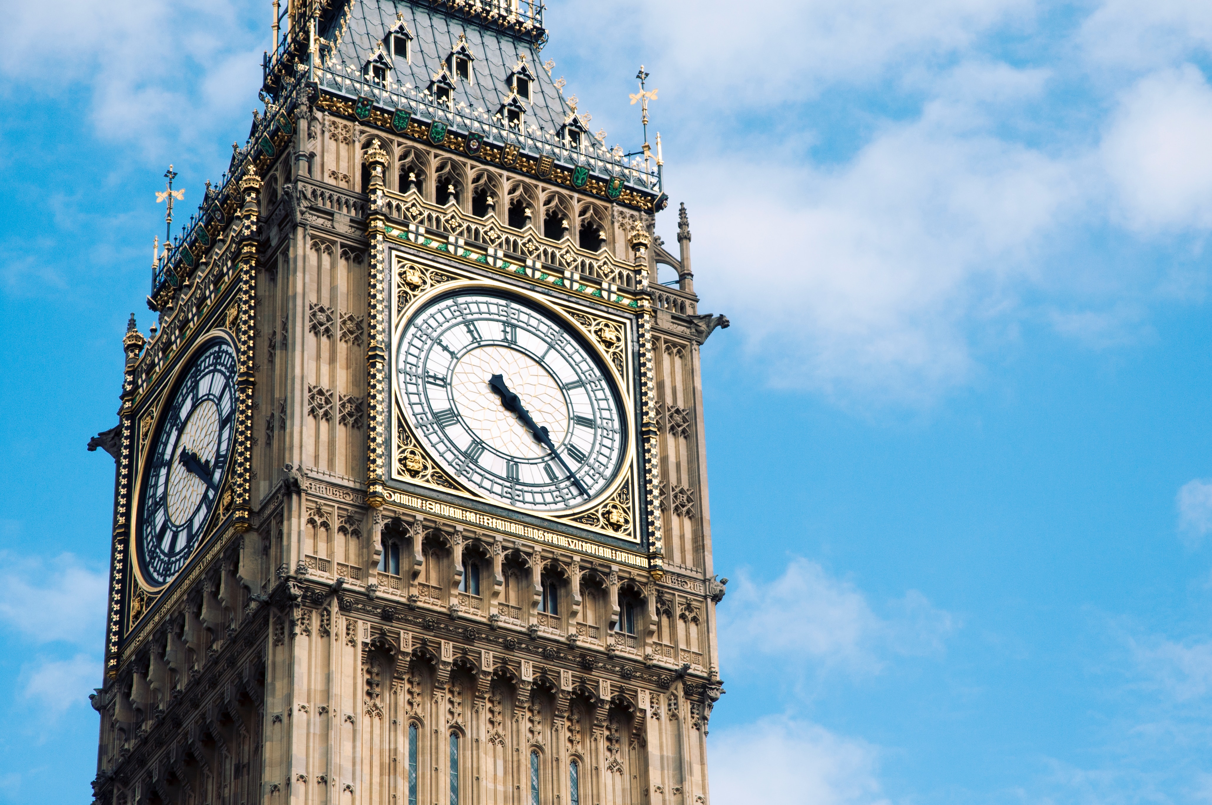 a clock tower with a weather vane with Big Ben in the background