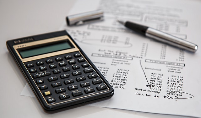 a calculator and pen on top of papers