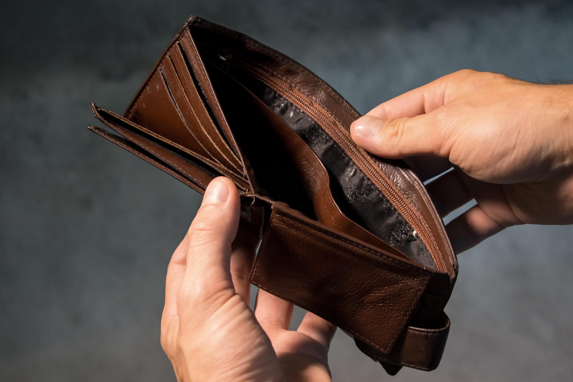 a hand holding a brown leather wallet