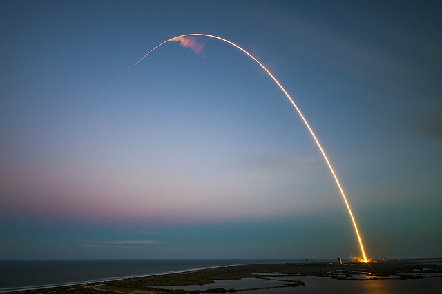 a rocket taking off from a launchpad with Wind Wand in the background