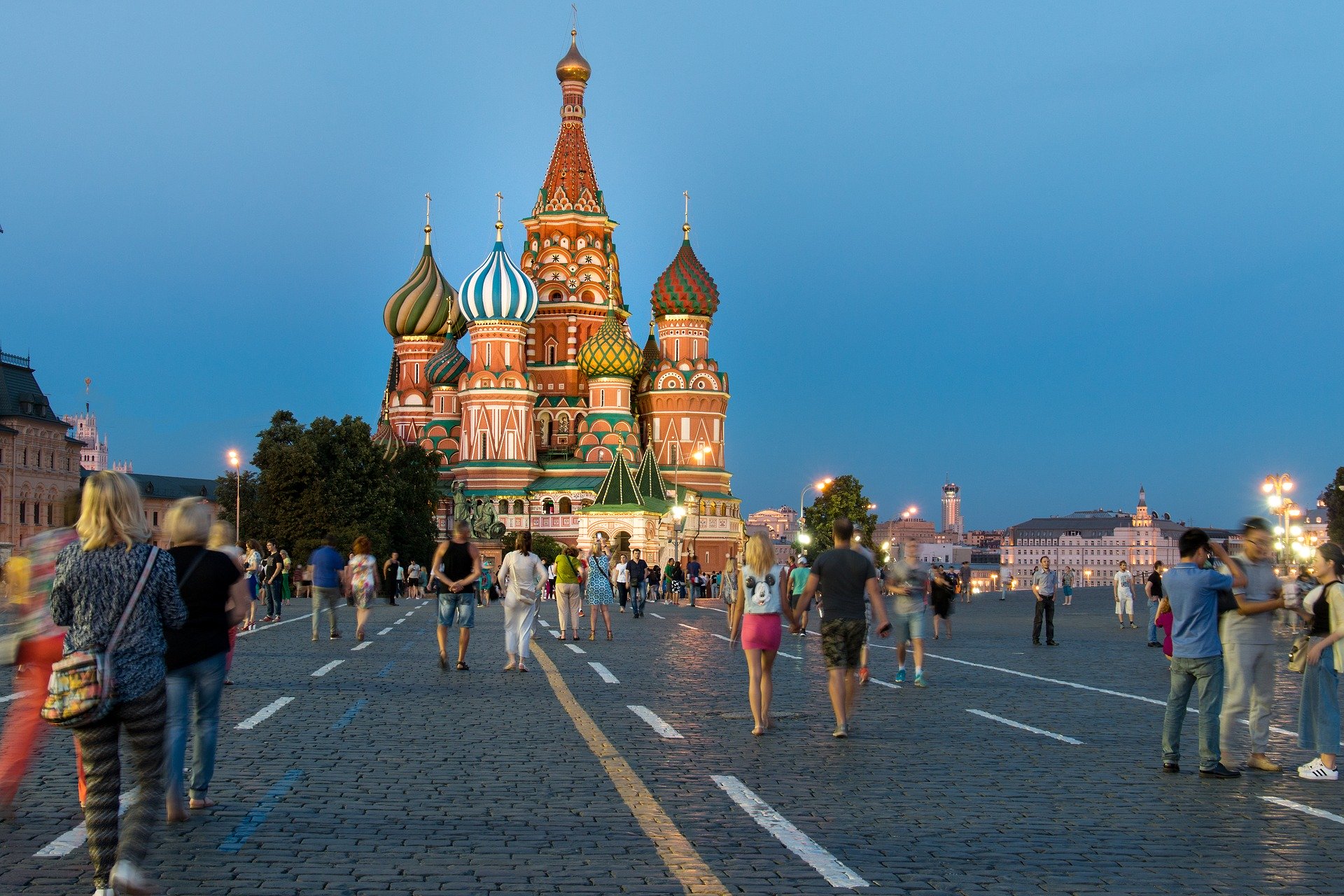 a crowd of people walking on a street in front of a colorful building