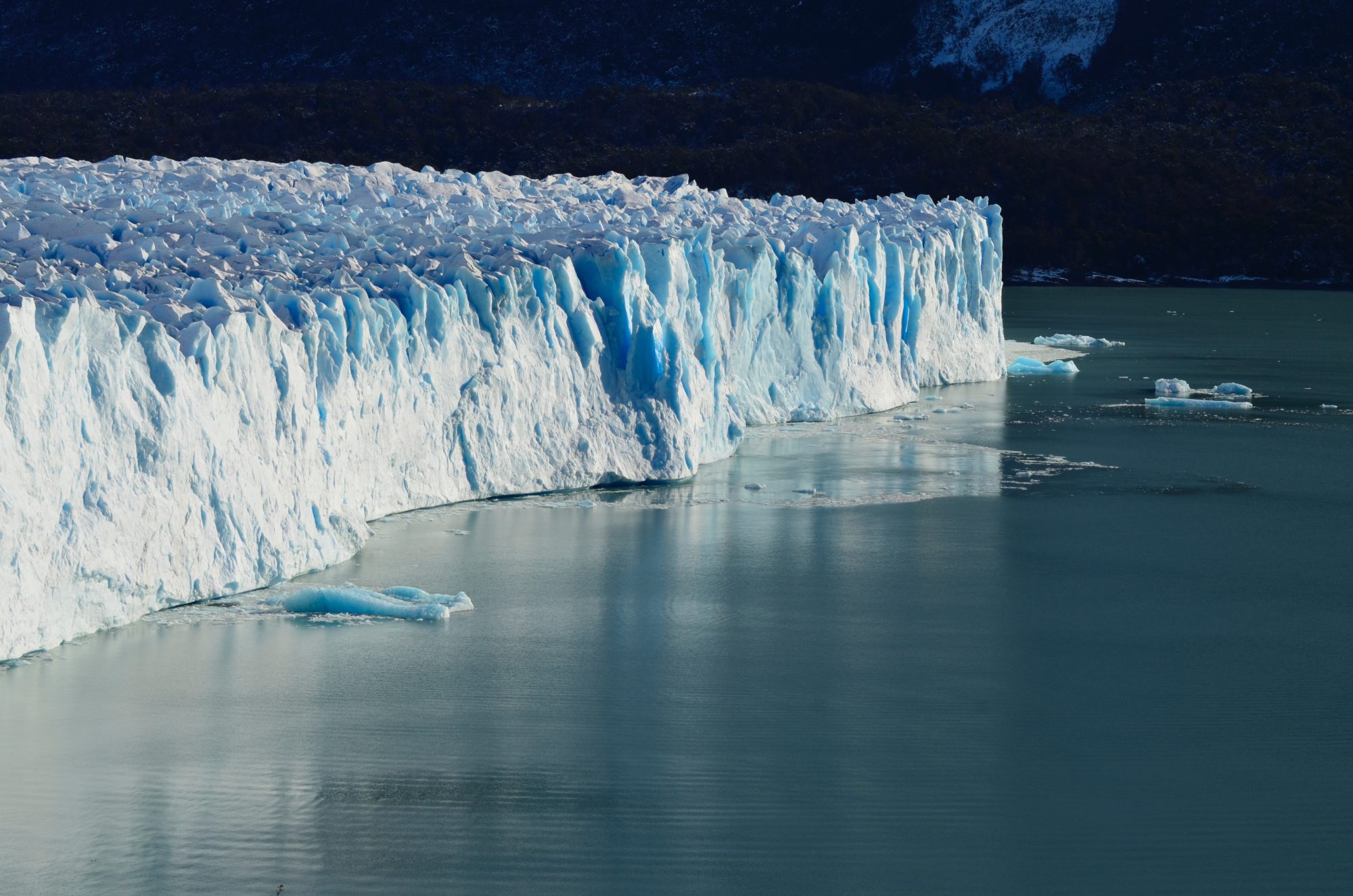 a large iceberg in the water with Perito Moreno Glacier in the background