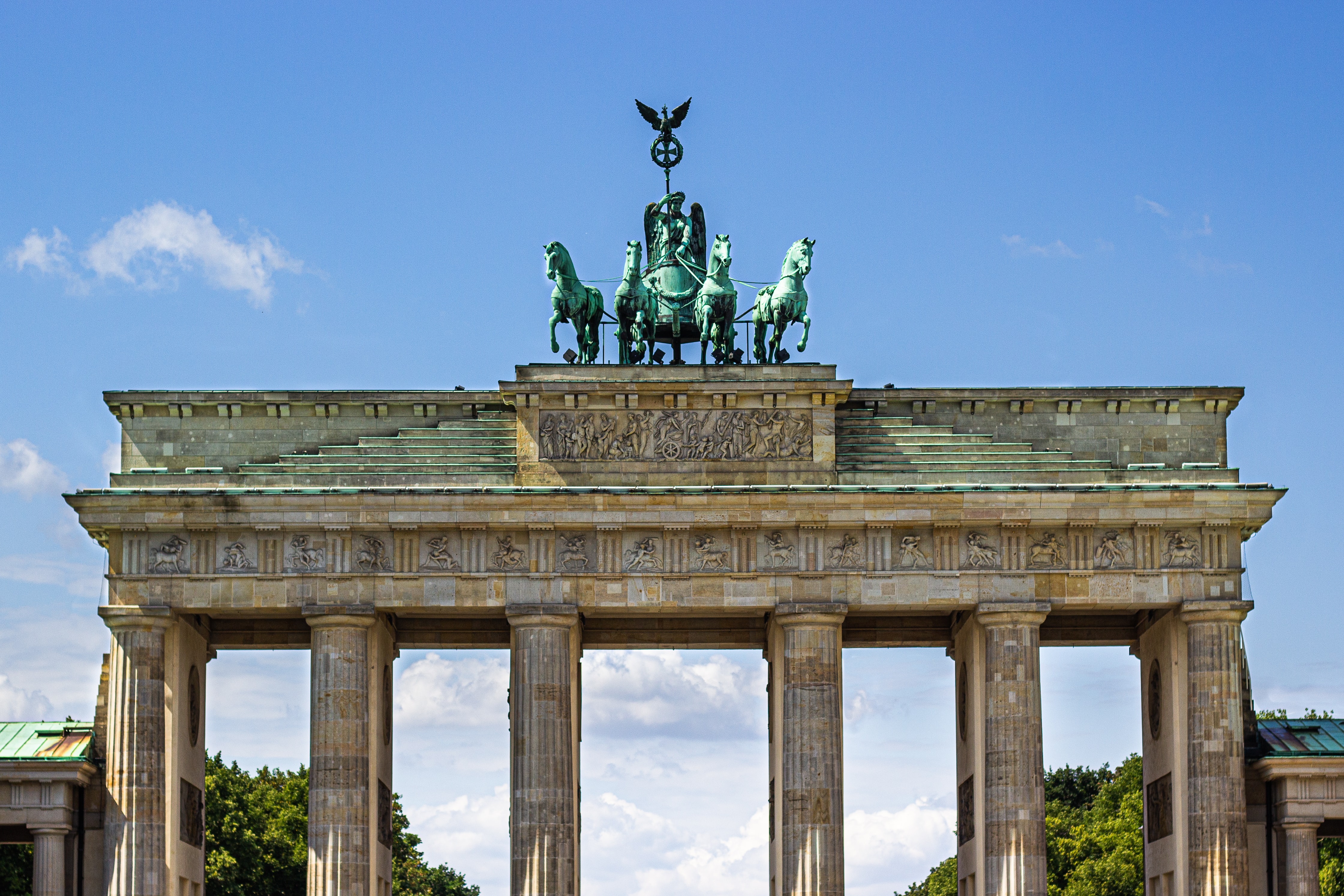 a large stone structure with statues on top with Brandenburg Gate in the background