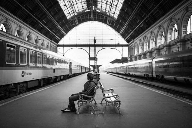 a person sitting on a bench next to a train
