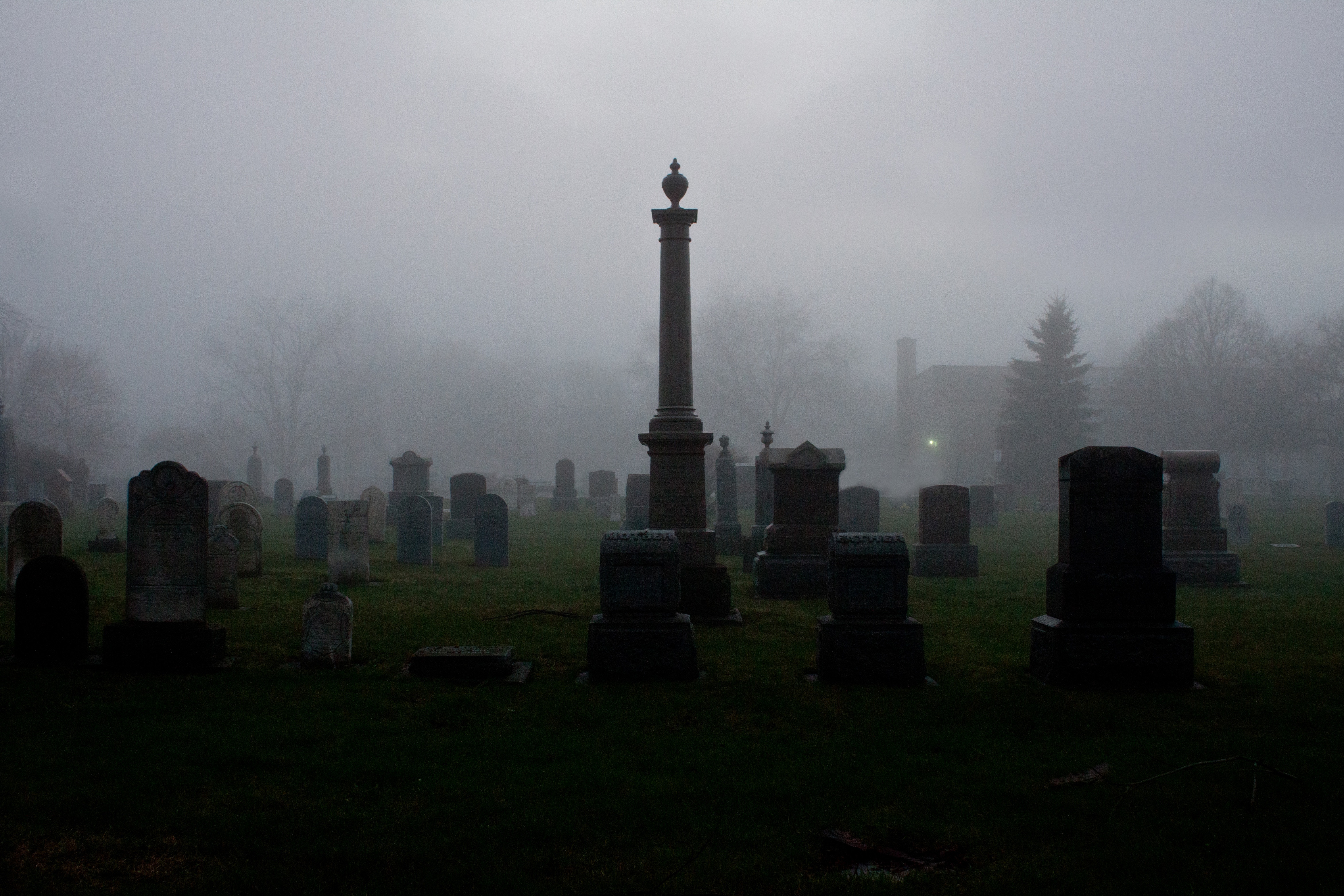 a cemetery with a tall tower in the fog