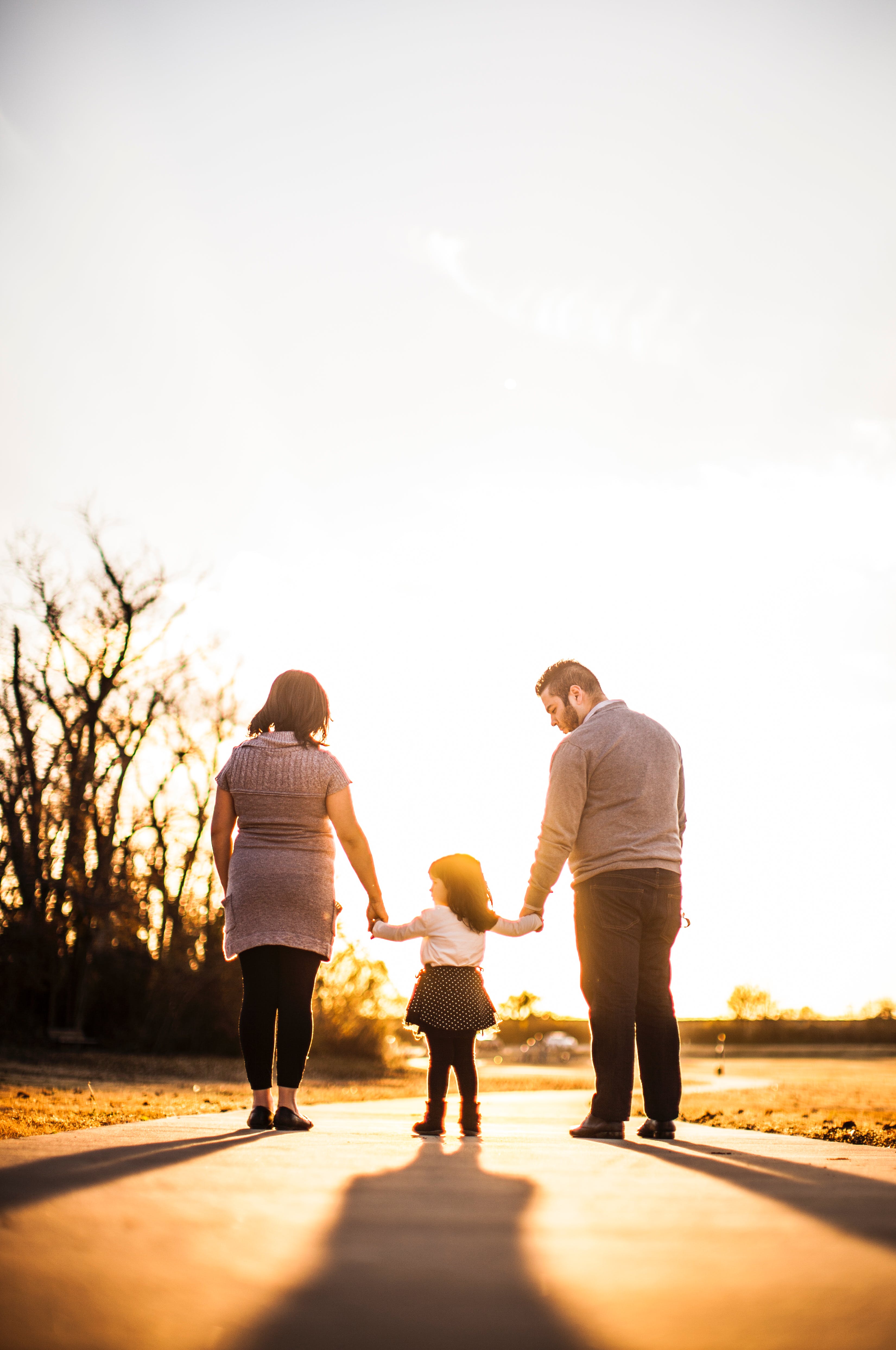Woman and man holding a child's hand walking