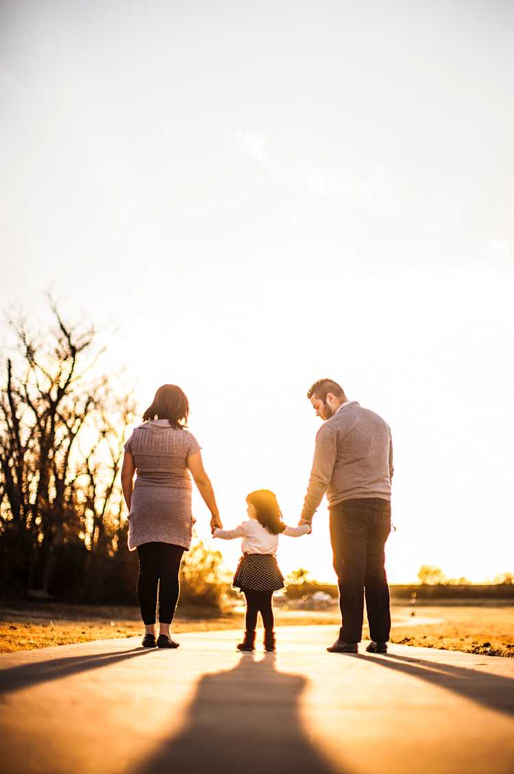 Woman and man holding a child's hand walking