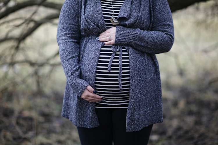 Pregnant woman, holding her tummy, in blue and white shirt