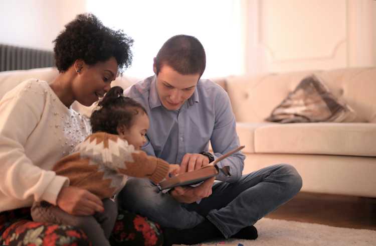 Photo of family sitting on floor while reading a book