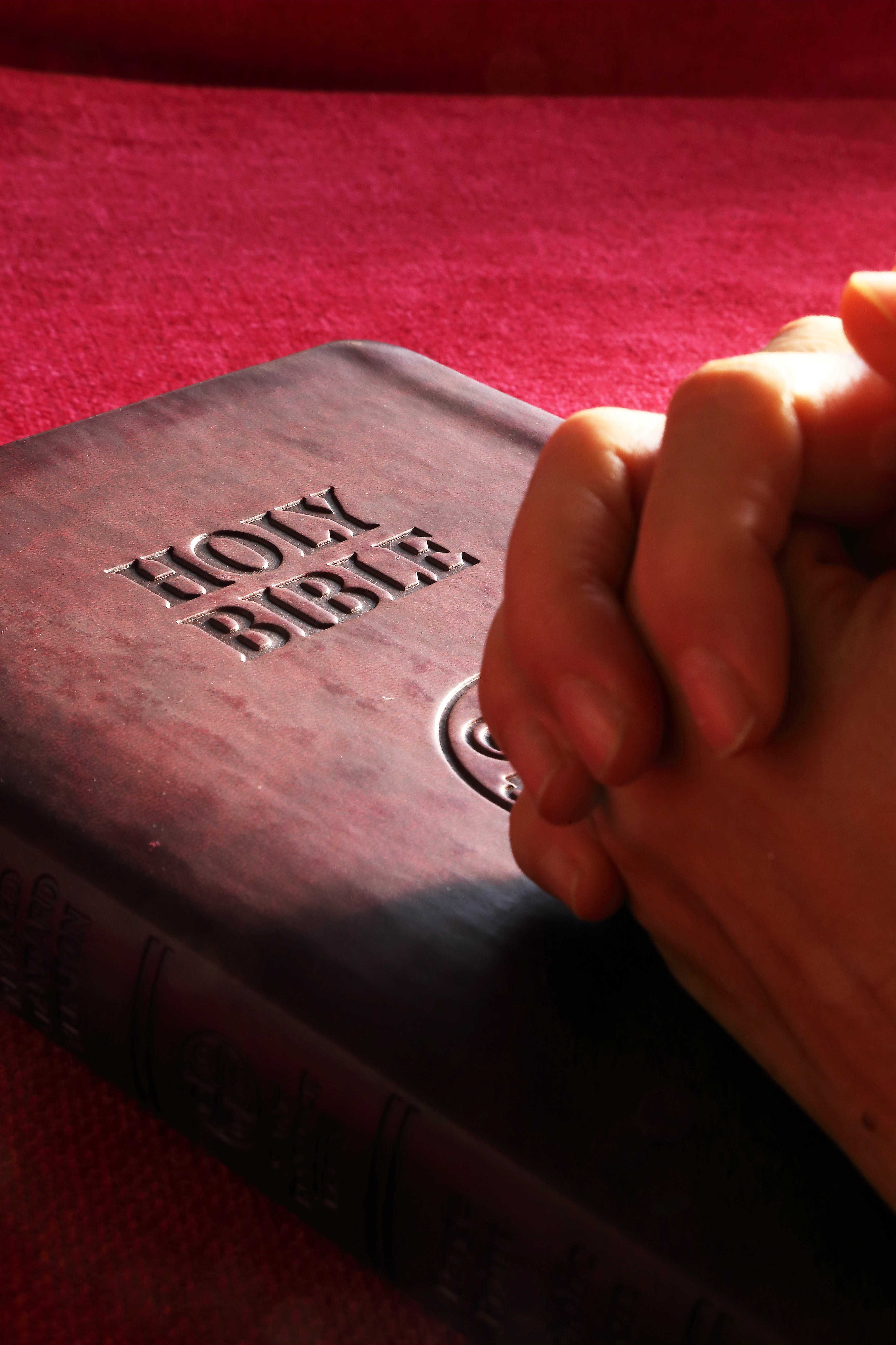 Hands linked together on a Holy Bible