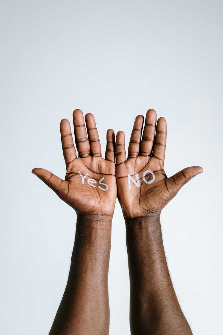 Photo of a person's hands with yes and no written on them