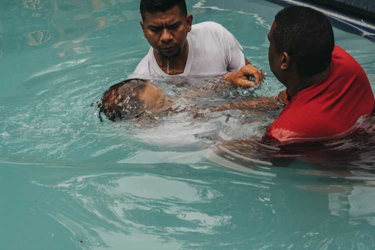 Two men baptizing a man