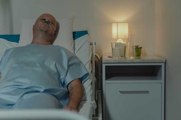Sick man lying on a hospital bed.