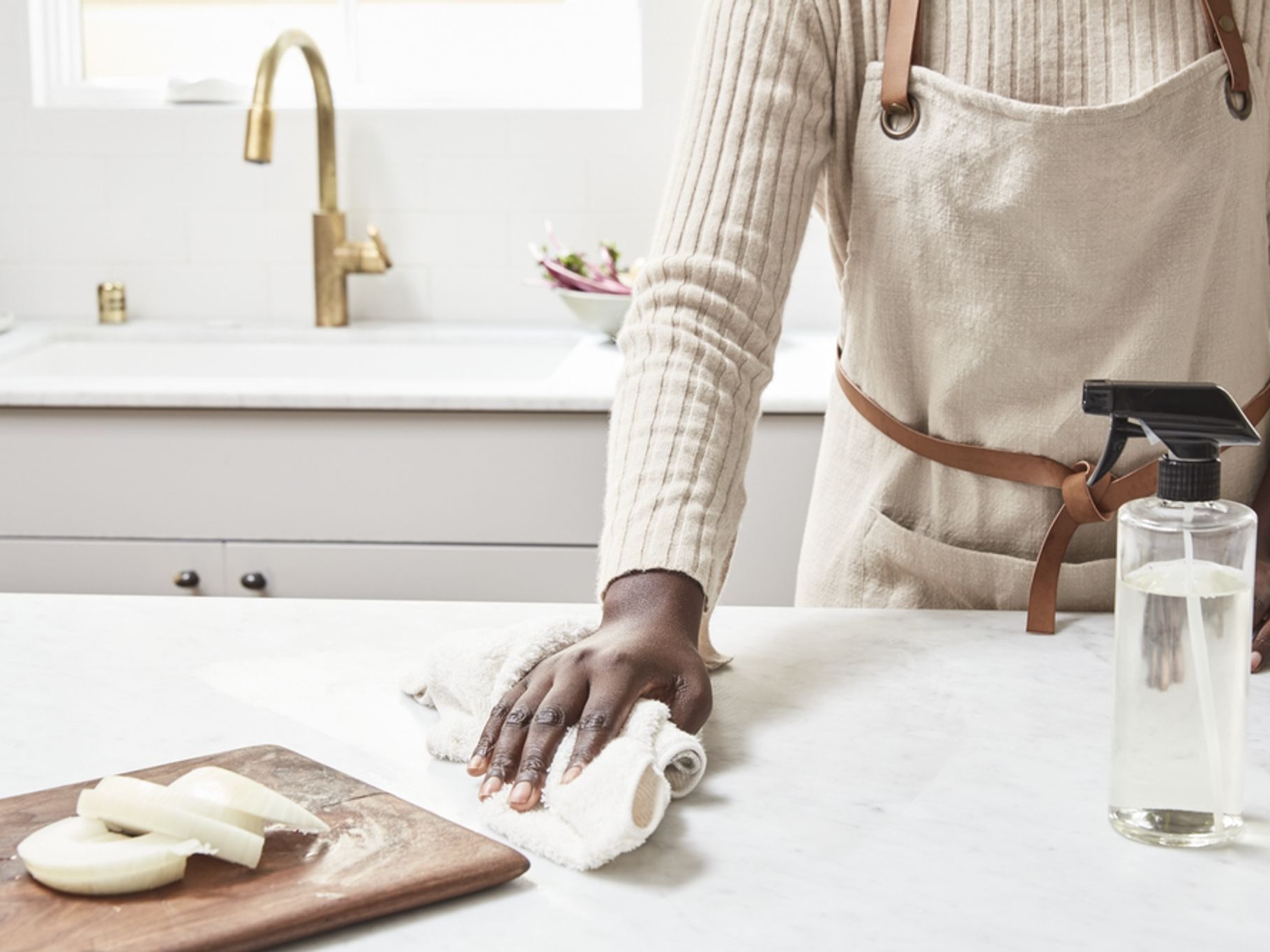 Image of woman wiping down kitchen counter next to cutting board