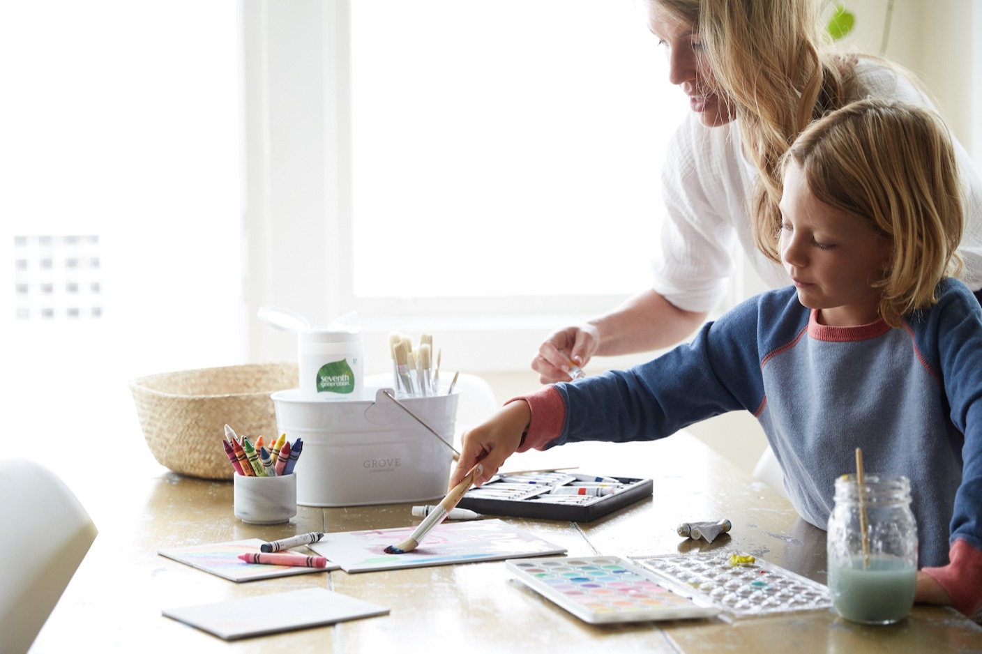 blonde mom and child doing watercolor painting at dining table
