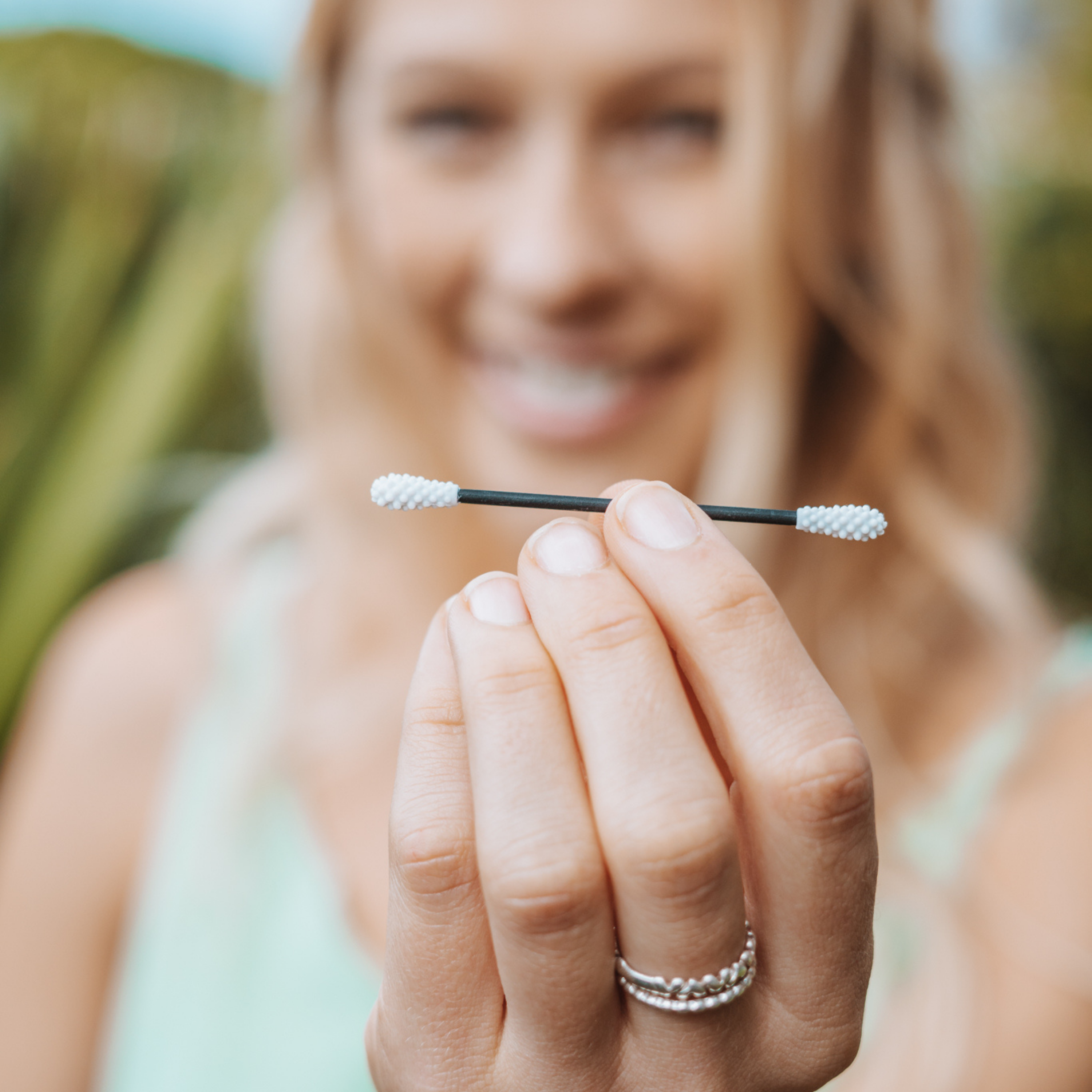 A woman holding up a reusable cotton swab.
