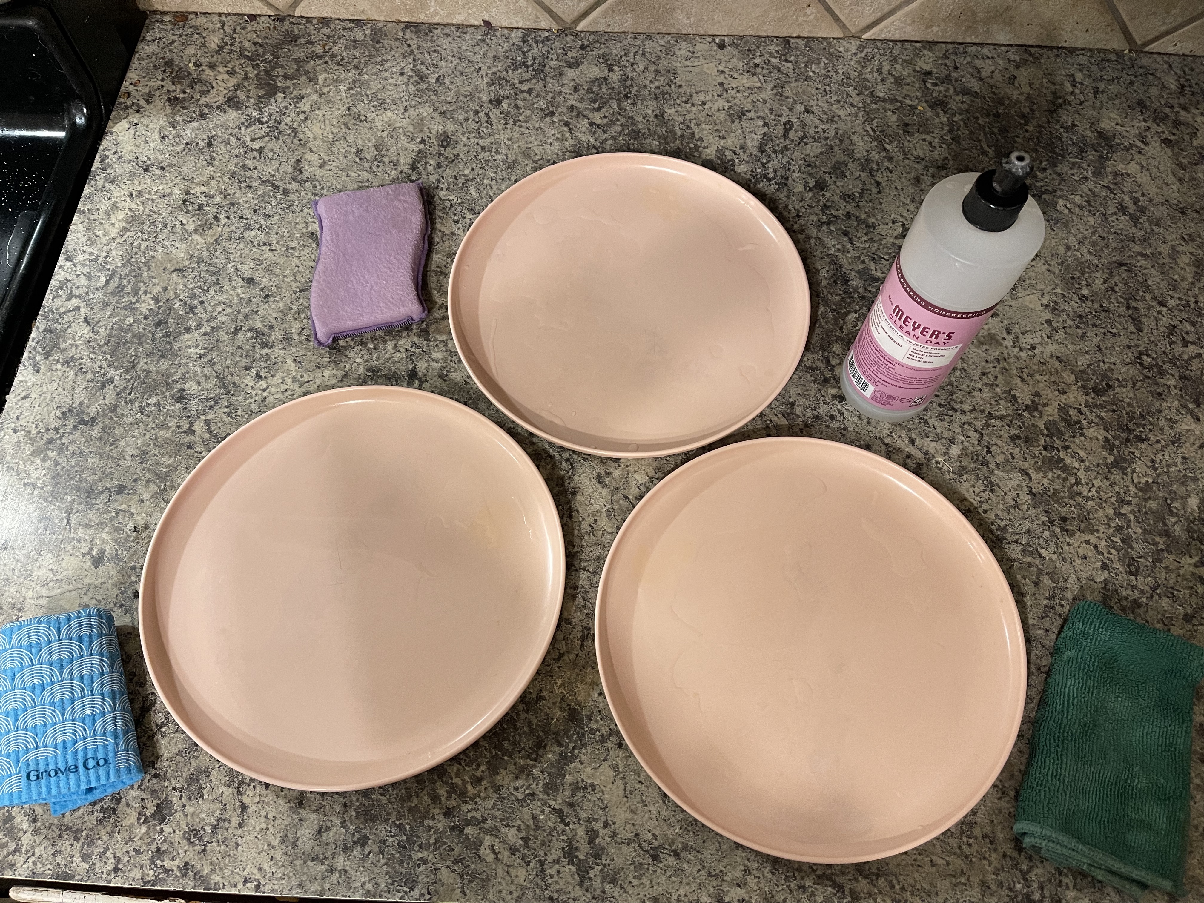 Three clean plates with European dish cloth, sponge and microfiber towel