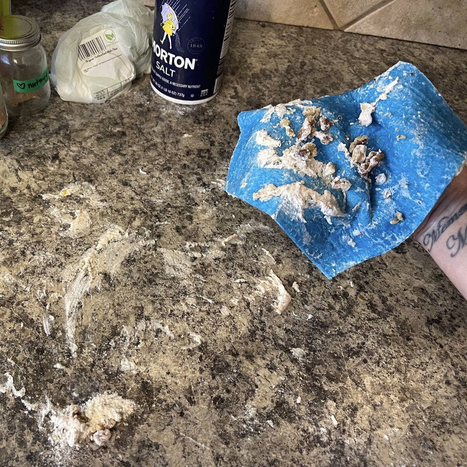 Messy counter after a baking project in the middle of being wiped up with a European dish cloth