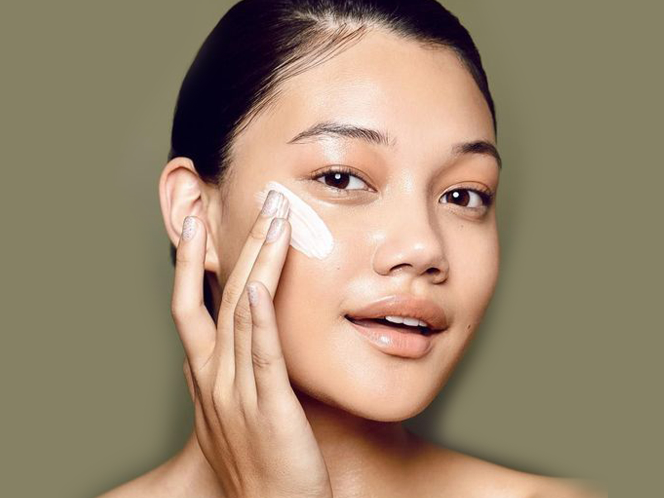 Image of a woman putting a product on her face. 