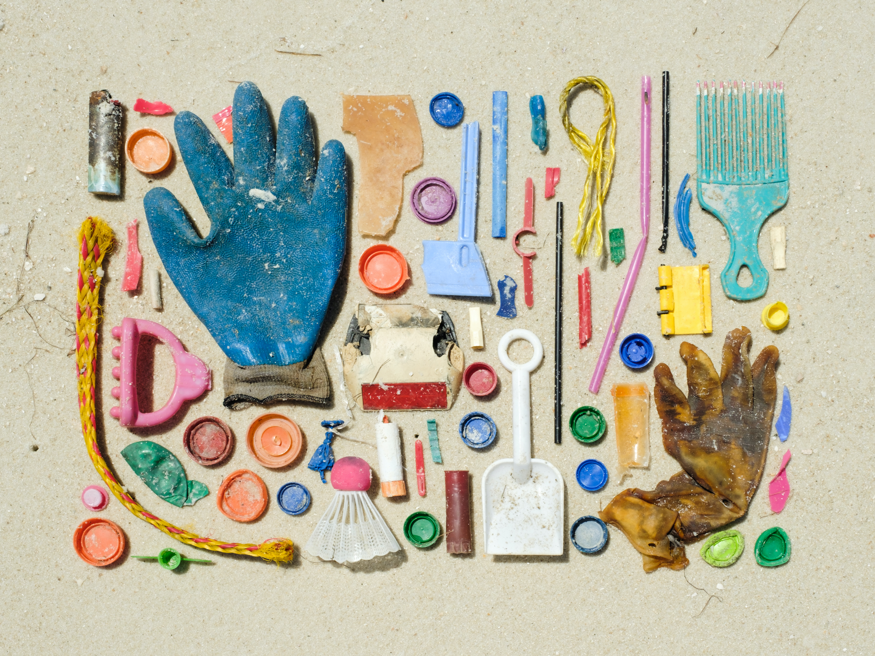 Organized pile of collected plastic on a sandy beach.