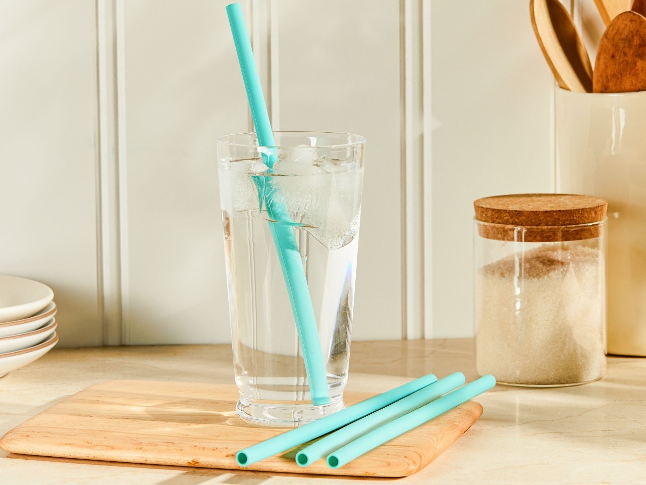 glass with silicone straw in it and other straws on cutting board on counter