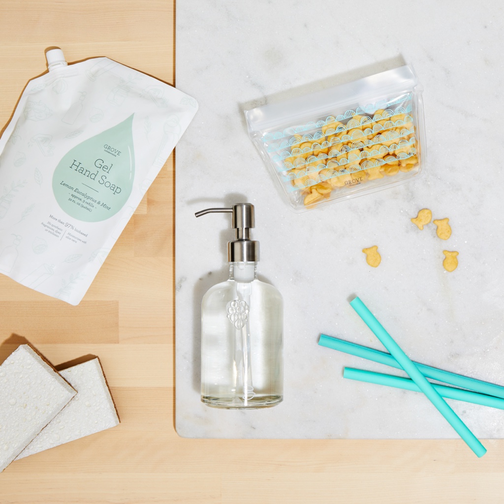 Flat lay of blue silicone straws, glass soap dispenser, and reusable snack bag