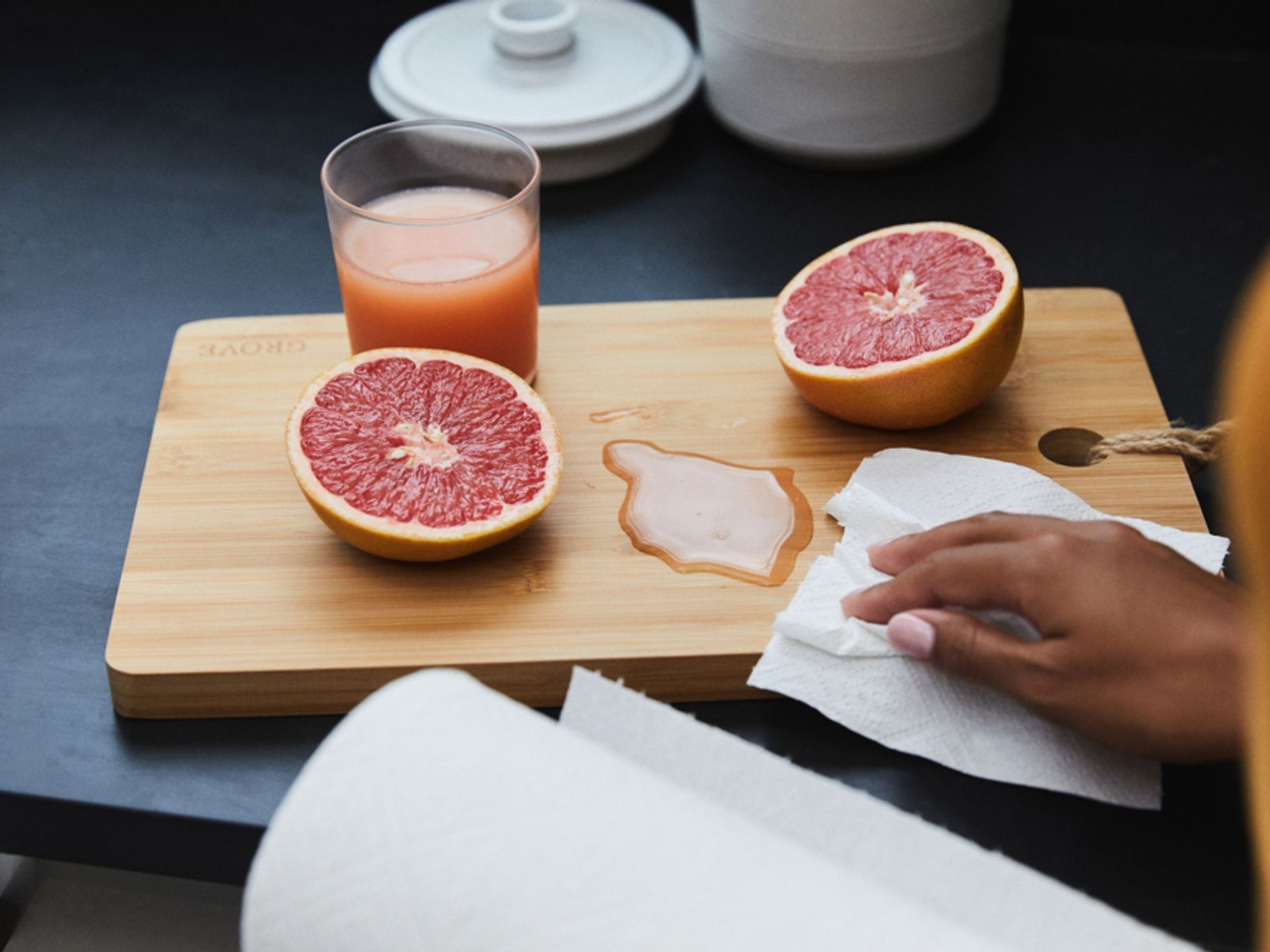 Hand wiping grapefruit juice with paper towel