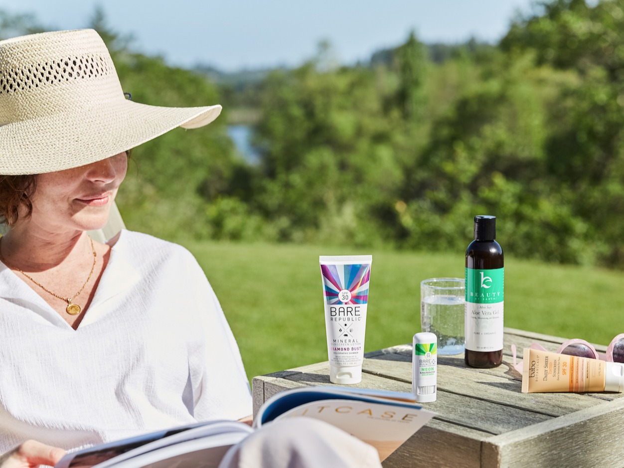Woman sitting outside next to table with suncreen products on it