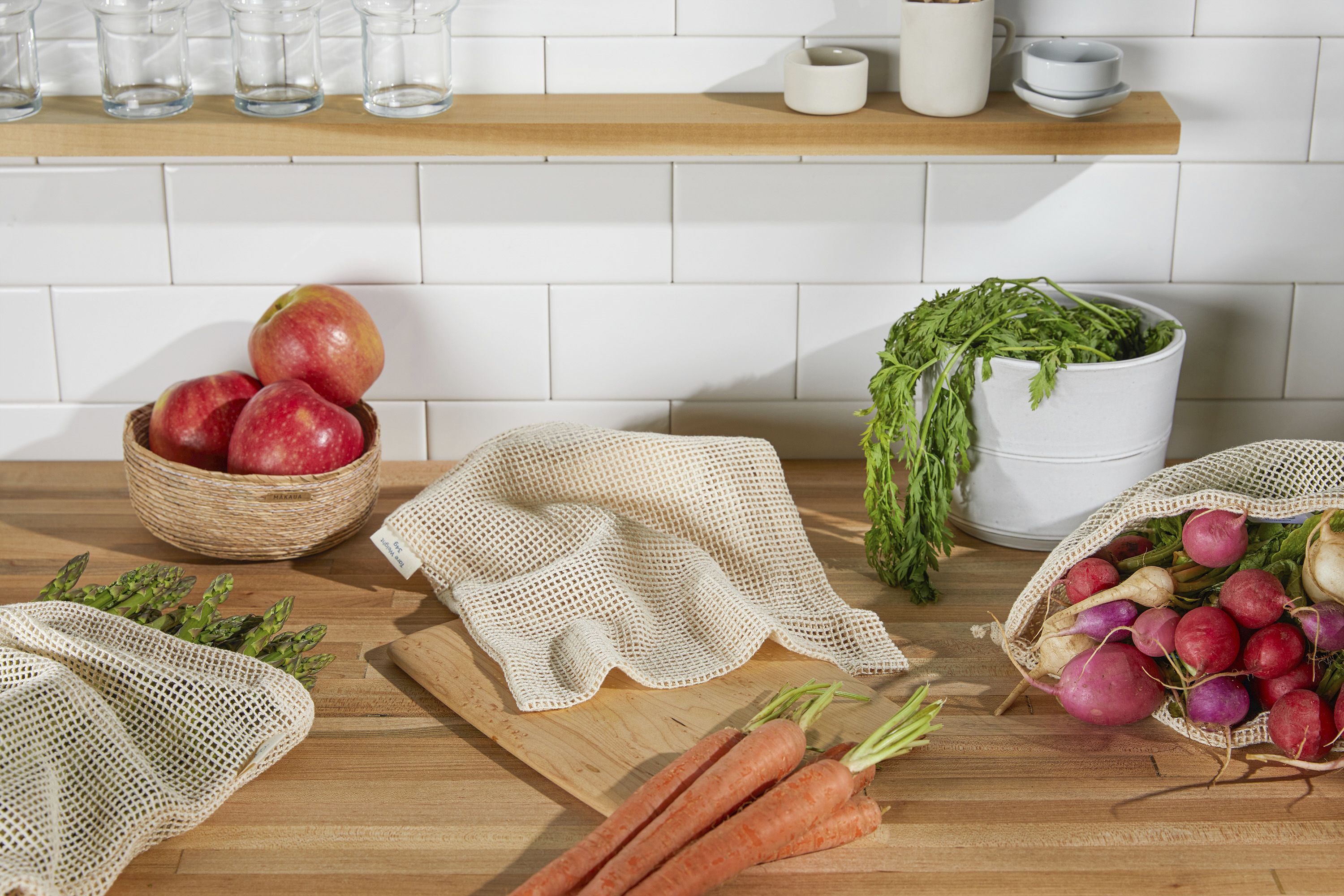 Images of vegetables on a counter with mesh bags in front of a white backsplash