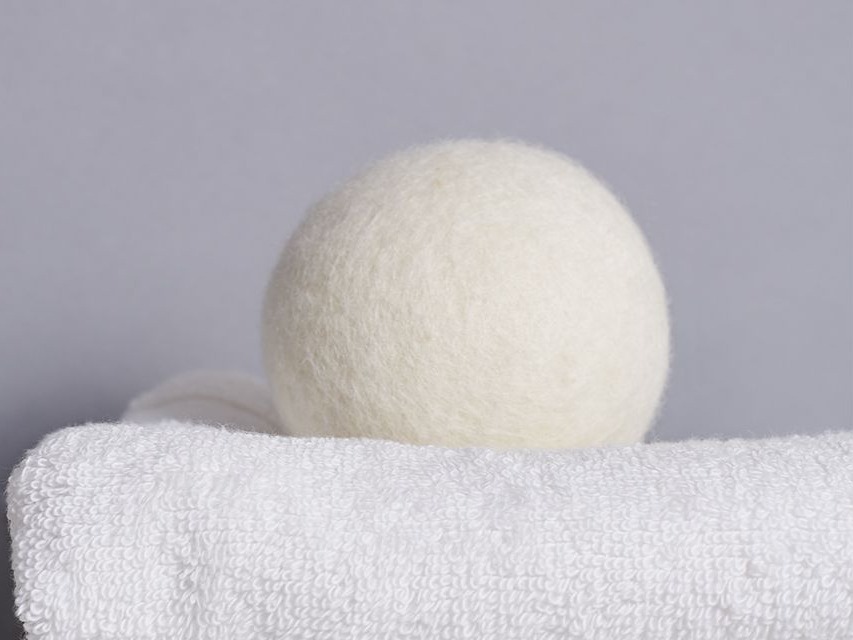Image of one white wool dryer ball on top of white folded towel