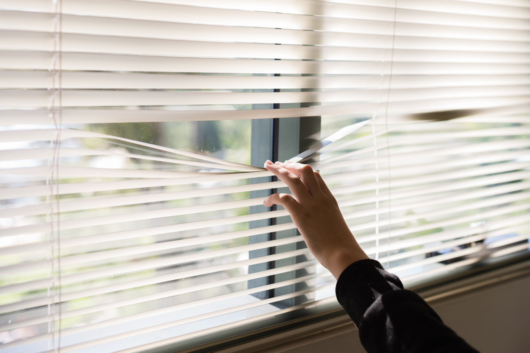 Image of someone looking through window blinds