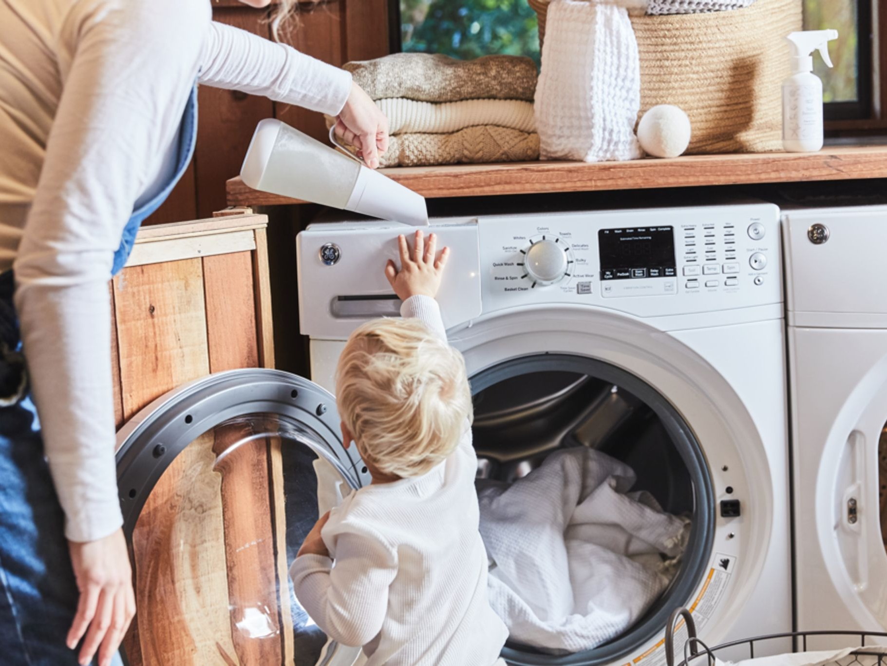Photo of woman and child adding laundry detergent to washing machine