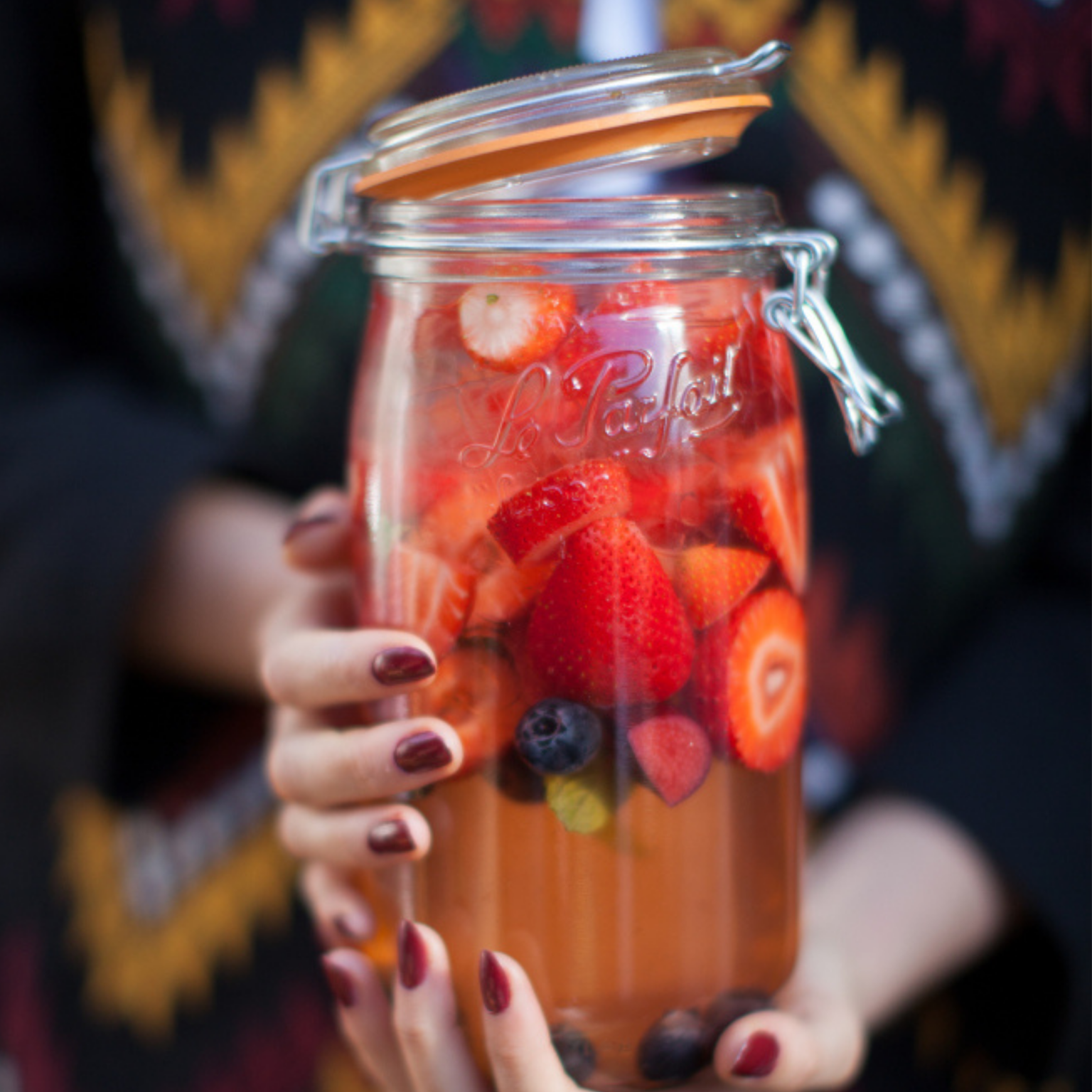 Image of a woman holding Le Parfait Glass Storage with berries and liquid inside.