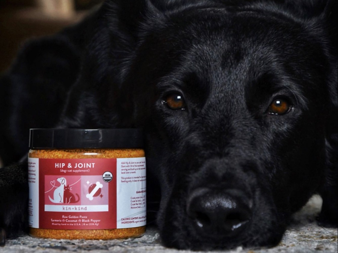 Image of a dog laying down next to Kin+Kind Healthy Hip and Joint Supplement for Dogs and Cats.
