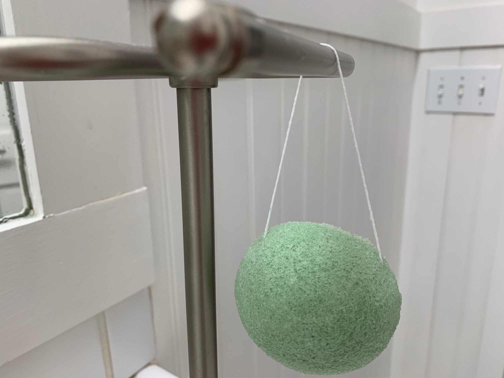 Image of green konjac sponge hanging by string to dry